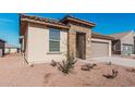 Single-story home with desert landscaping, a stone-accented entryway, and an attached two-car garage at 20660 N Confetti Ct, Maricopa, AZ 85138