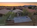 Charming single-story home with desert landscaping, concrete driveway, and mountain views at sunset at 22139 N Van Loo Dr, Maricopa, AZ 85138