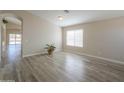 Open-concept living room with light-colored walls, hardwood floors, a large window, and an arched doorway at 22139 N Van Loo Dr, Maricopa, AZ 85138