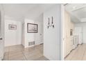 Bright hallway with tiled floor, leading to kitchen with white cabinets and appliances at 11139 W Cameo Dr, Sun City, AZ 85351