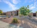 Charming single-story home with desert landscaping, mature trees, rock accents, and a well-maintained lawn at 11256 S Hopi Dr, Goodyear, AZ 85338