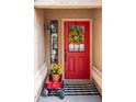 A welcoming red front door is adorned with a sunflower wreath, complemented by a potted plant on wheels at 1514 E Hearne Way, Gilbert, AZ 85234