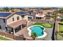 Aerial shot of the backyard, displaying a custom pool, putting green, patio, and desert landscaping at 18225 W Mackenzie Dr, Goodyear, AZ 85395