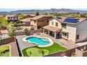 Aerial view of a private backyard featuring a uniquely shaped pool, putting green, and covered patio at 18225 W Mackenzie Dr, Goodyear, AZ 85395