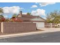 Side view of a one-story home with a brick wall, lush bougainvillea and two-car garage at 1938 N 67Th St, Mesa, AZ 85205