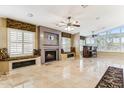 Spacious living room with a modern fireplace, custom window seats, and elegant tile flooring at 19927 N 108Th Ln, Sun City, AZ 85373