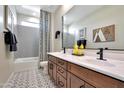 Bright bathroom featuring double sinks, modern fixtures, patterned tile floors, and a shower and tub combination at 44327 N 43Rd Dr, Phoenix, AZ 85087