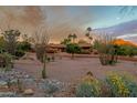 Sprawling desert home with mature landscaping, including palm trees and desert flora, under a colorful sky at 6845 N Hillside Dr, Paradise Valley, AZ 85253