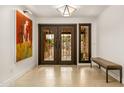 Elegant foyer with travertine flooring, striking double doors, bench, and unique artwork at 6845 N Hillside Dr, Paradise Valley, AZ 85253