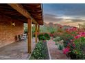 Charming covered porch with comfortable seating surrounded by vibrant flowers and desert landscaping at 6845 N Hillside Dr, Paradise Valley, AZ 85253