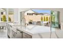 Close-up of kitchen island with a white countertop, stainless steel sink, and view of backyard with pool at 9370 E Wethersfield Rd, Scottsdale, AZ 85260