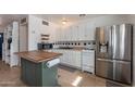 Efficient kitchen layout with white cabinetry, stainless steel refrigerator, and central island at 99 W Circle Dr, Florence, AZ 85132