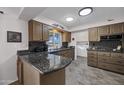 Well-lit kitchen featuring granite countertops, wooden cabinetry, tile floors, and modern appliances at 10019 W Shasta Dr, Sun City, AZ 85351