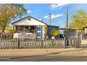 Cozy home featuring a charming porch with decorative flowers, a picket fence, and a well-manicured lawn at 1546 W Polk St, Phoenix, AZ 85007