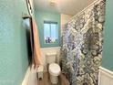 Bright bathroom featuring a decorative shower curtain, white wainscoting, and wood-look floors at 1636 E Marigold St, Casa Grande, AZ 85122