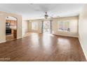 Open living room with hardwood floors, a ceiling fan, large windows and an archway leading to the kitchen at 1655 W Wilson Ave, Coolidge, AZ 85128