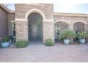 Inviting front entrance featuring stone archways, mature landscaping, and a solid wood door at 20187 E Sonoqui Blvd, Queen Creek, AZ 85142