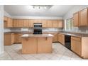 Bright kitchen with large island, black appliances, and ample cabinet space at 24118 W Desert Bloom St, Buckeye, AZ 85326