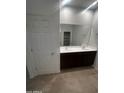 Bathroom with double sinks, dark wood cabinetry, large mirror, and tiled floors at 37582 W San Clemente St, Maricopa, AZ 85138