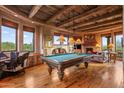 Entertaining game room featuring a pool table, exposed beam ceilings and a stone fireplace at 41731 N Stone Cutter Dr, Scottsdale, AZ 85262