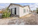 Side view of a charming home featuring a stucco exterior, black shutters, stone accents, and a spacious yard at 625 W Central Ave, Coolidge, AZ 85128