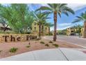 Inviting community entrance with stone signage, lush landscaping and palm trees lining the roadway at 7130 W Linda Ln, Chandler, AZ 85226