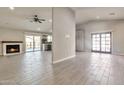 Bright living room featuring a brick fireplace, light grey tile flooring, and access to the kitchen at 726 E Aire Libre Ave, Phoenix, AZ 85022