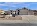 A tan single Gathering home showcasing desert landscaping, a barrel tile roof and a large 3-car garage at 1635 E Silverwood Dr, Phoenix, AZ 85048