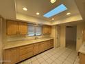 Bright kitchen featuring a skylight, tile flooring, and plenty of storage space at 18034 N 129Th Ave, Sun City West, AZ 85375