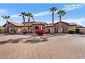 Daytime view of a home featuring desert landscaping and mature palm trees lining the property and brick driveway at 5203 N 179Th Dr, Litchfield Park, AZ 85340