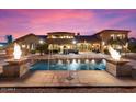 Twilight view of a backyard with a stunning pool with water features, and an outdoor seating area at 5203 N 179Th Dr, Litchfield Park, AZ 85340