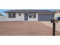 Charming single-story home with desert landscaping and a gray two-car garage door at 702 N Evergreen St, Gilbert, AZ 85233