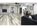 View of open concept living room with brick fireplace and gray wood flooring connecting to the kitchen and playroom at 718 W Paseo Way, Tempe, AZ 85283