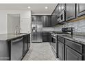 Modern kitchen with stainless steel appliances, dark cabinetry, and a stylish tiled backsplash for added appeal at 3263 S Miller Dr, Chandler, AZ 85286