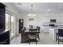 Open concept dining area with modern lighting fixture, neutral color palette, and easy kitchen access at 47558 W Mellen Ln, Maricopa, AZ 85139