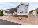 Inviting manufactured home features desert landscaping and a brick-paved driveway leading to a covered carport at 7750 E Broadway Rd # 54, Mesa, AZ 85208