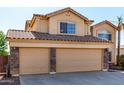 A three car garage featuring tan doors, stone accents, and a concrete driveway at 835 E Stirrup Ln, San Tan Valley, AZ 85143