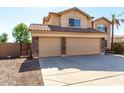 A three car garage featuring tan doors, stone accents, and a concrete driveway at 835 E Stirrup Ln, San Tan Valley, AZ 85143