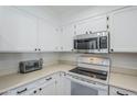 Well-lit kitchen showcasing white cabinetry, stainless steel microwave, and an electric stove at 9275 E Mission Ln # 206, Scottsdale, AZ 85258