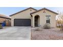 Inviting home featuring a two-car garage, desert landscaping, and an arched entryway at 9539 W Agora Ln, Tolleson, AZ 85353