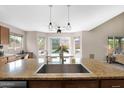 Kitchen showcases granite counters, stainless steel sink, modern pendant lights, and natural light at 13641 W Solano Dr, Litchfield Park, AZ 85340