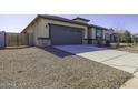 Exterior view of a home with a gray garage door and neutral colored stucco, landscaping, and long driveway at 38197 W San Clemente St, Maricopa, AZ 85138
