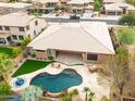 Expansive backyard featuring a sparkling pool, lush landscaping, and covered patio with outdoor seating at 15146 W Highland Ave, Goodyear, AZ 85395