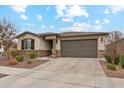 Inviting single-story home with stone veneer, a paved driveway, manicured landscaping, and an attached two-car garage at 16278 W Jenan Dr, Surprise, AZ 85379