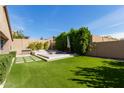 An inviting backyard featuring artificial grass, desert landscaping, and a built-in BBQ at 3025 W Night Owl Ln, Phoenix, AZ 85085