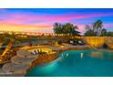 Inviting pool and spa featuring a waterfall, lounge chairs, lush landscaping, and beautiful sunset views at 3400 E Isaiah Ave, Gilbert, AZ 85298