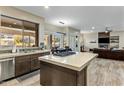 Kitchen with a large island and stainless steel dishwasher, open to the living room with fireplace at 5210 E Danbury Rd, Scottsdale, AZ 85254