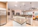 Open kitchen with a spacious island, stainless steel appliances, and sliding glass doors at 6159 W Sequoia Dr, Glendale, AZ 85308