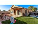 View of the home's backyard with green grass, block wall, covered patio, and beige exterior at 815 E Centre Ave, Buckeye, AZ 85326