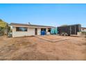 A flat dirt lot backyard is shown with a trailer and blue trash receptacles near the house at 11512 E 6Th Ave, Apache Junction, AZ 85120